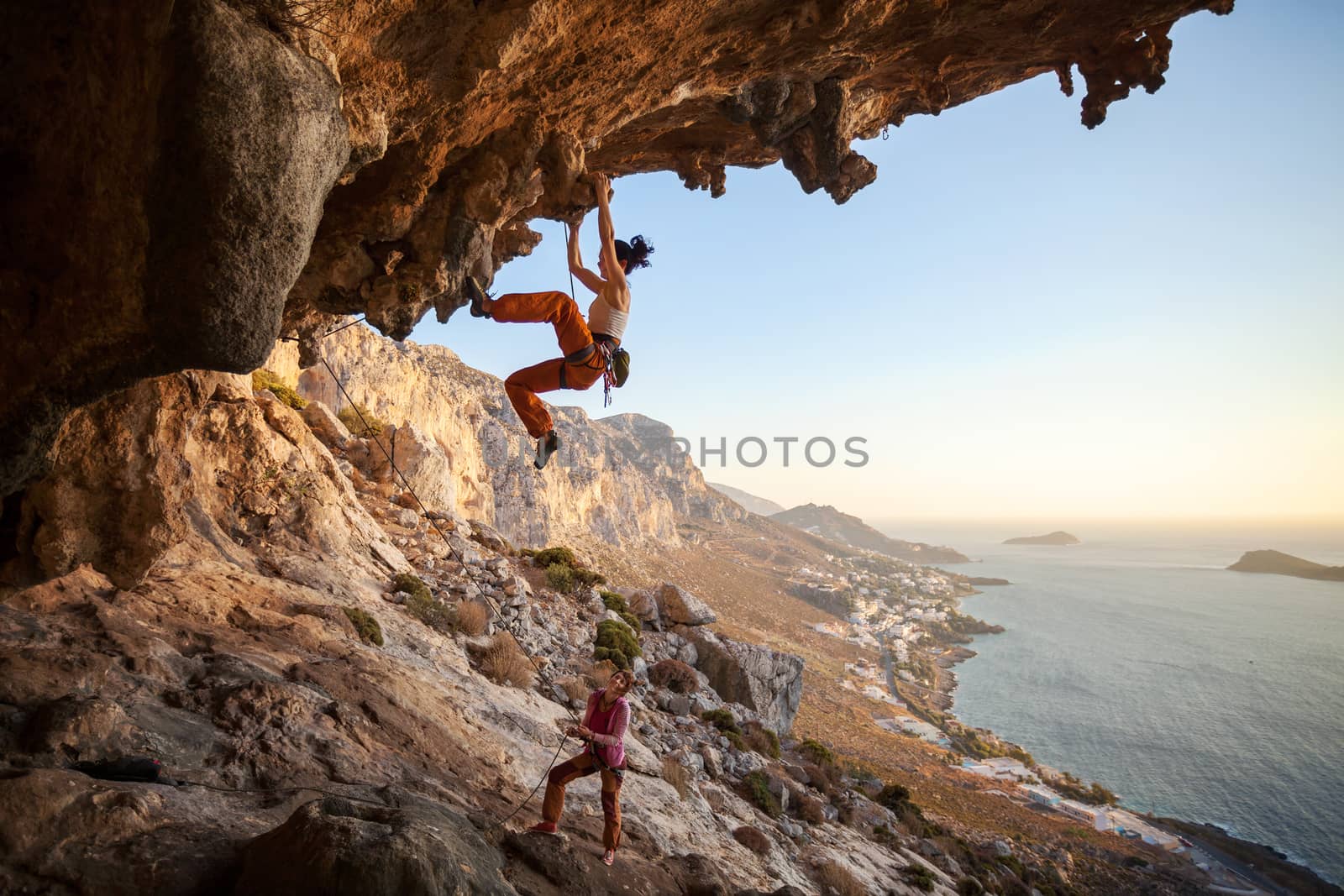 Young woman lead climbing in cave with beautiful view in background