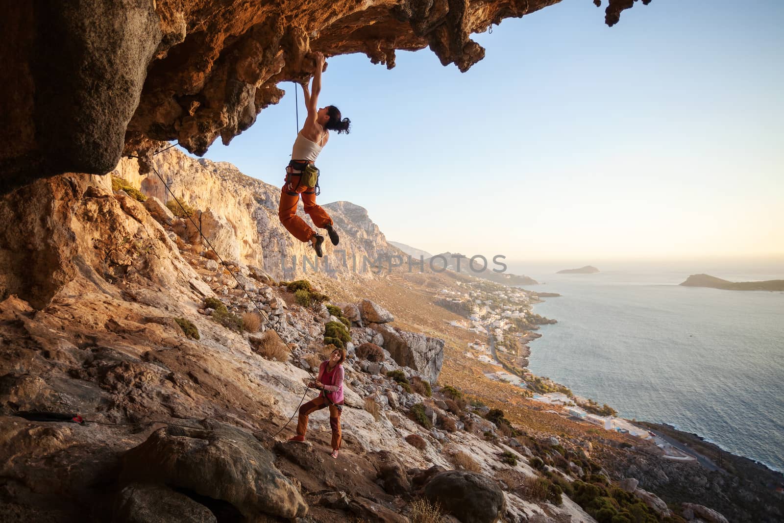 Young woman lead climbing on overhanging cliff by photobac