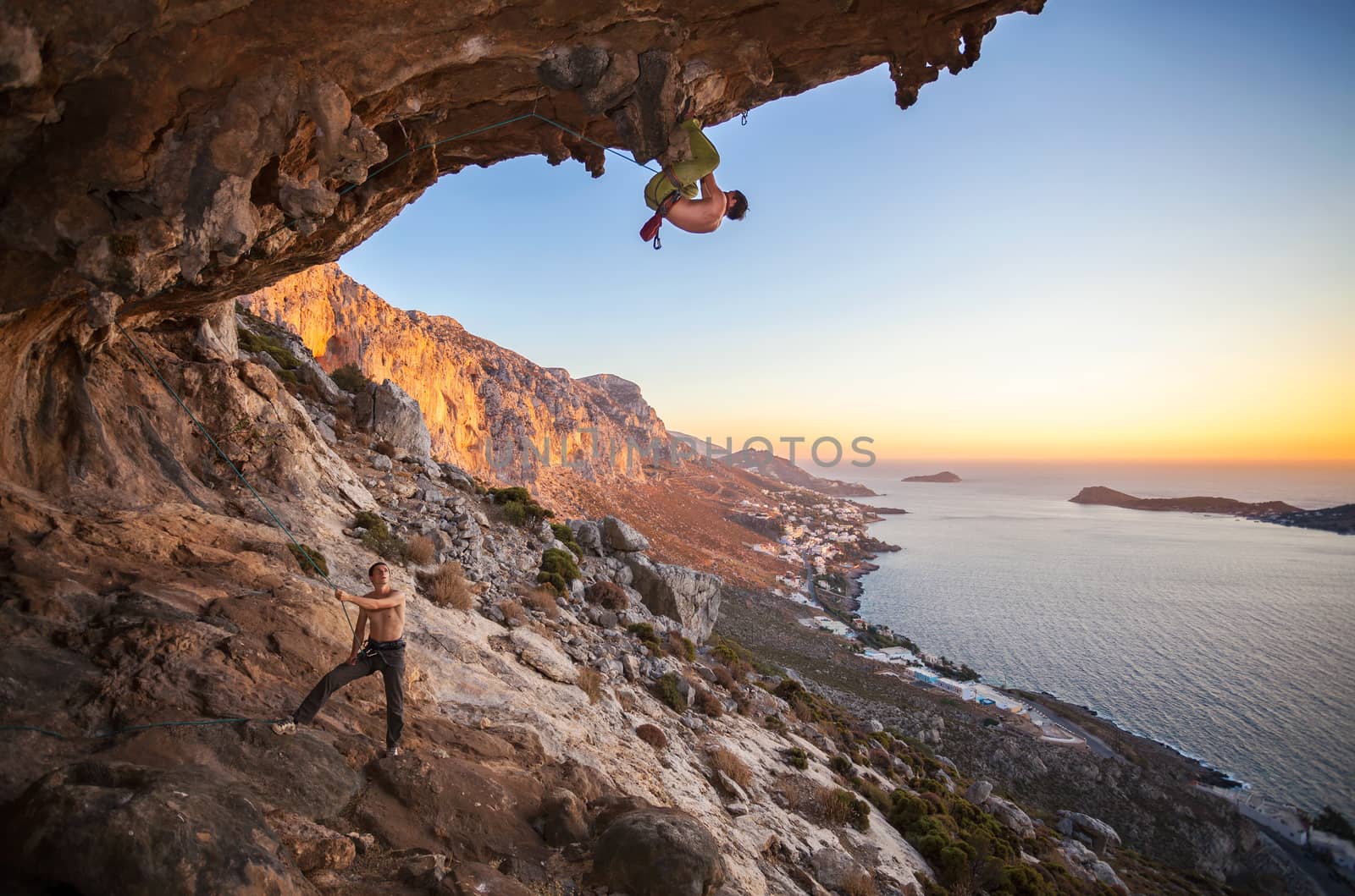 Male rock climber climbing on a roof in a cave by photobac