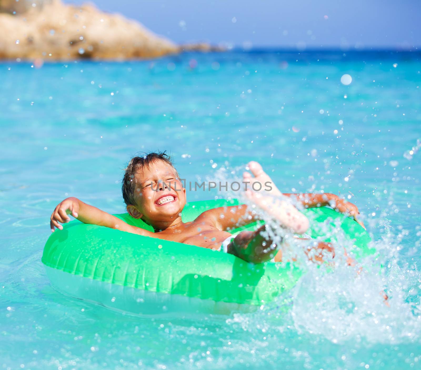 Happyboy playing on the inflatable rubber circle in the sea