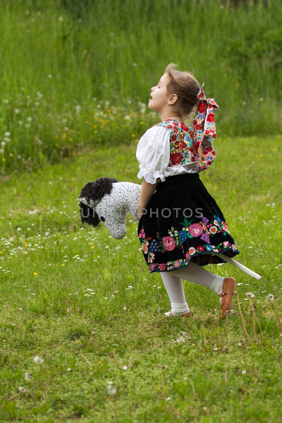 Little girl running around the meadow with tailstock