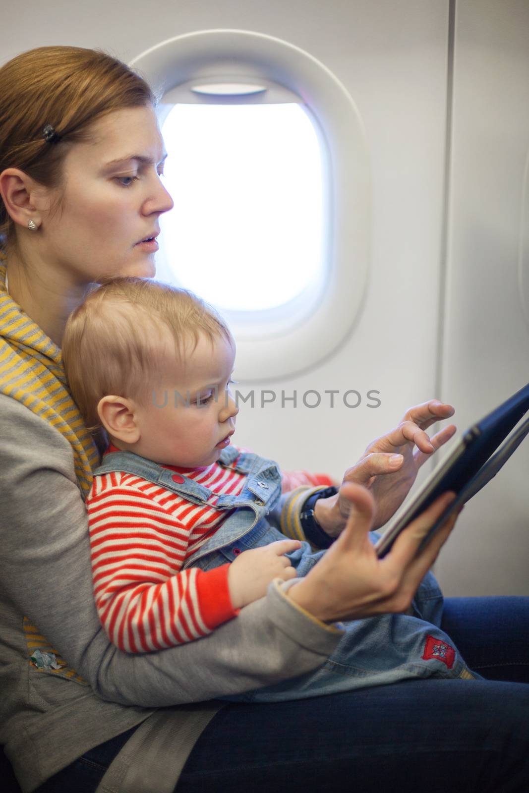 Mother and baby son on board of airplane by photobac
