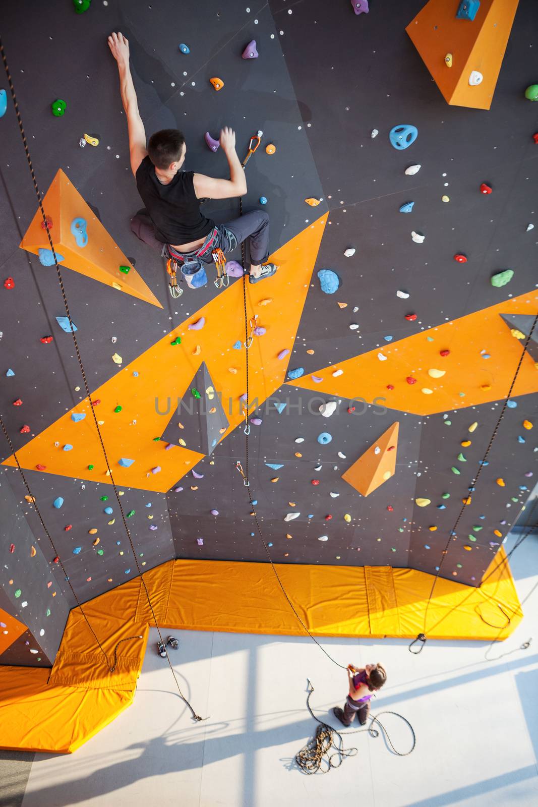 Young man practicing rock-climbing on a rock wall indoors