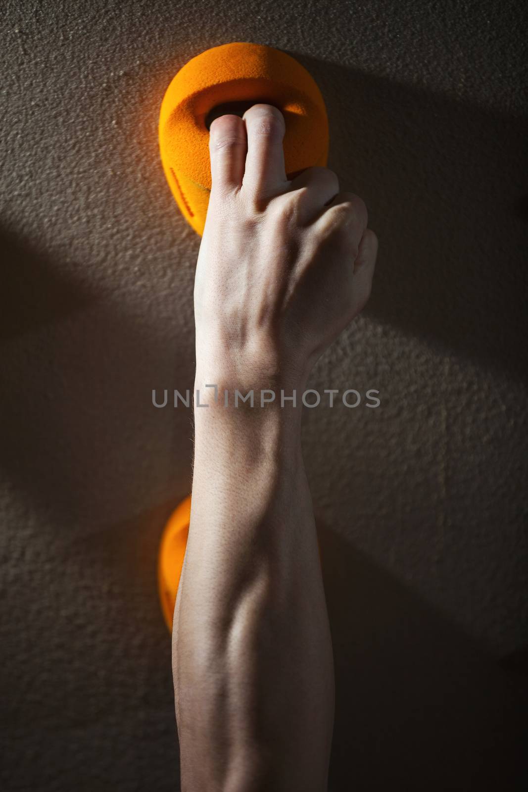 Cropped view of rock climber gripping handhold with two fingers