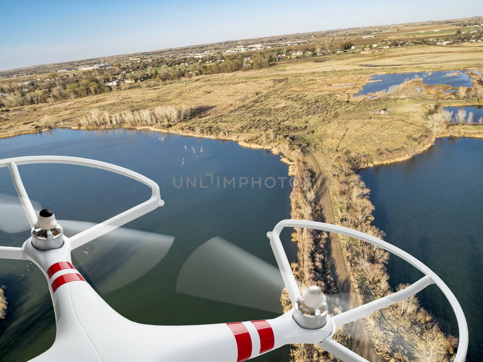 rotating propellers of an airborne quadcopter drone flying over lake and swamp landscape in northern Colorado, early spring