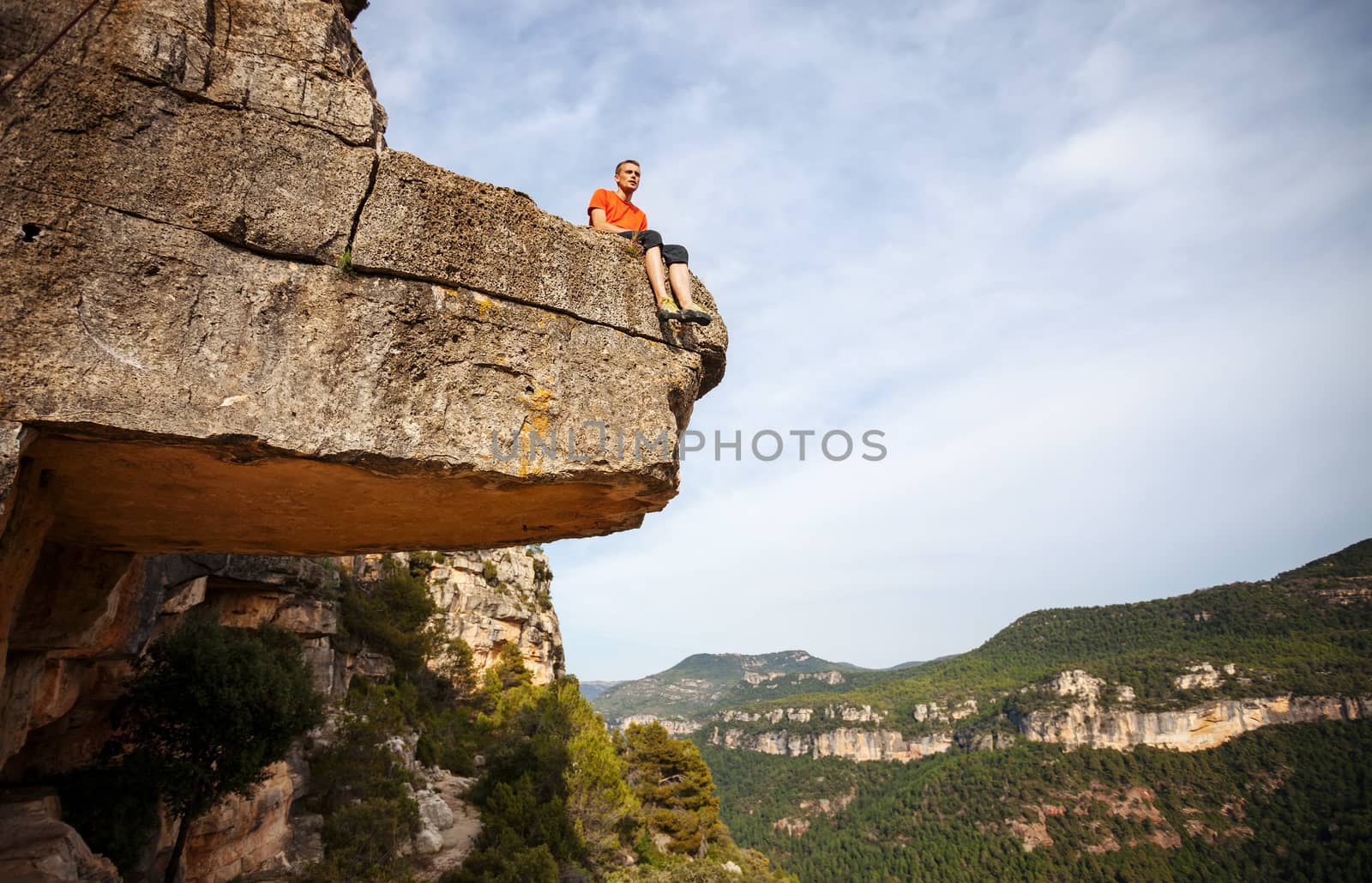 Pensive man sitting on edge of cliff by photobac