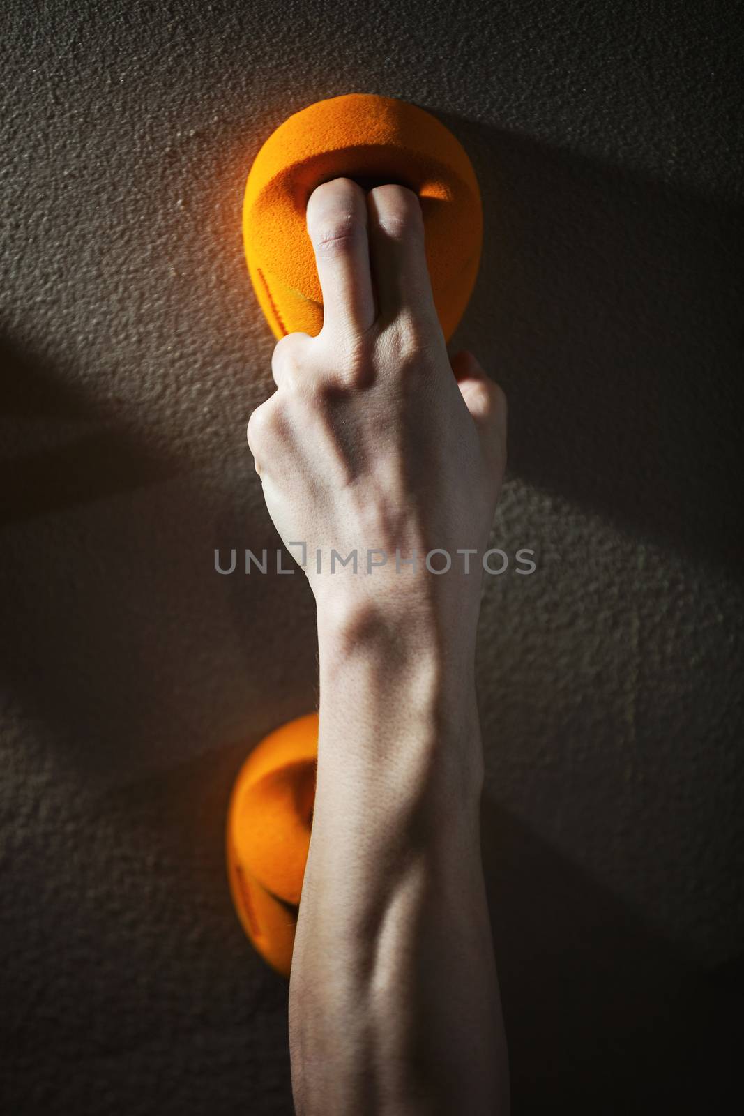 Cropped view of rock climber gripping handhold by photobac