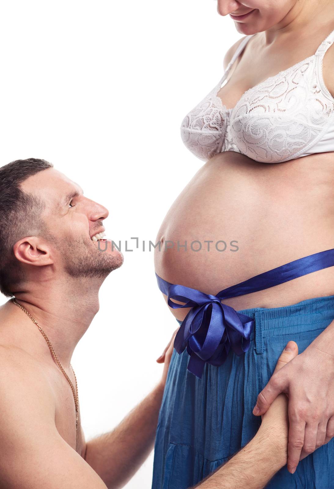 Cheerful young man looking at his pregnant wife over white background