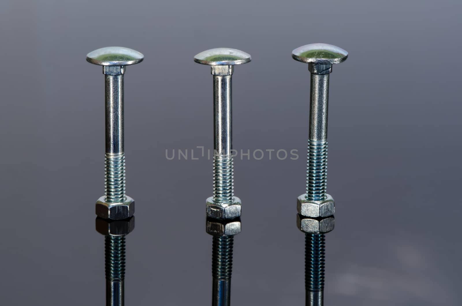 Three metal screw with nice reflection on black background.