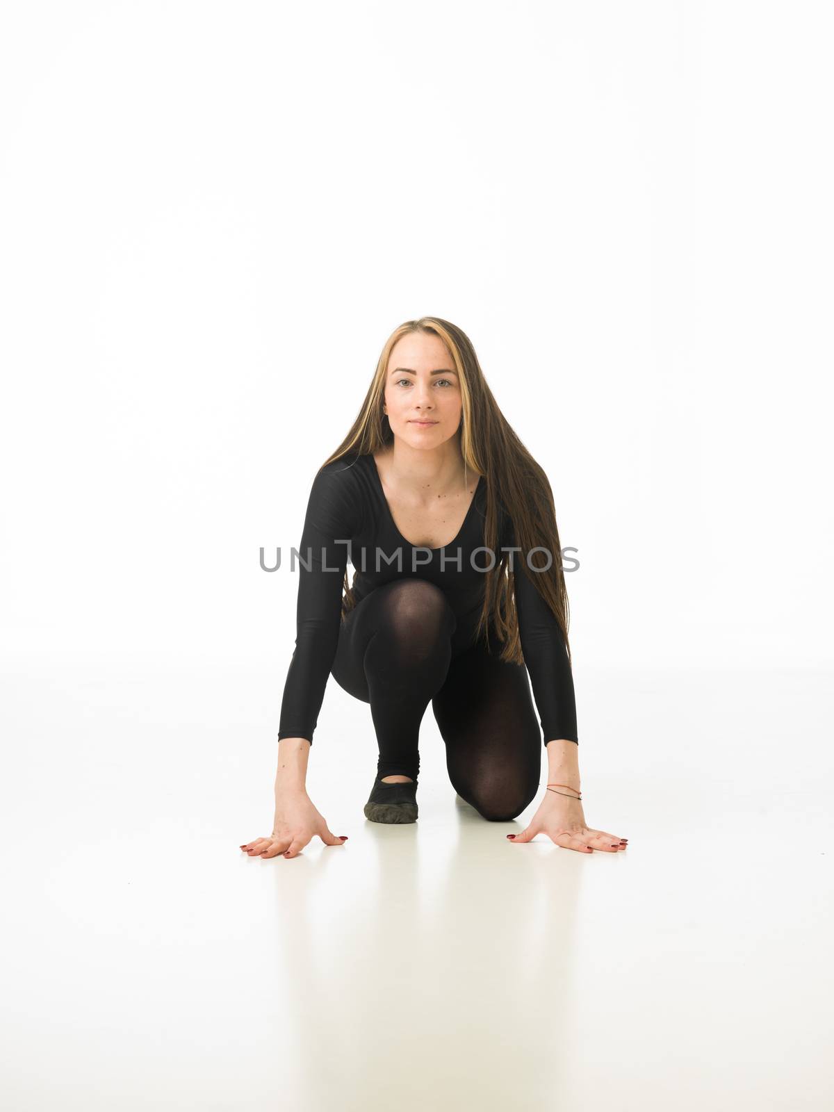 beautiful ballet dancer sitting on studio floor looking in front of the camera, on white background