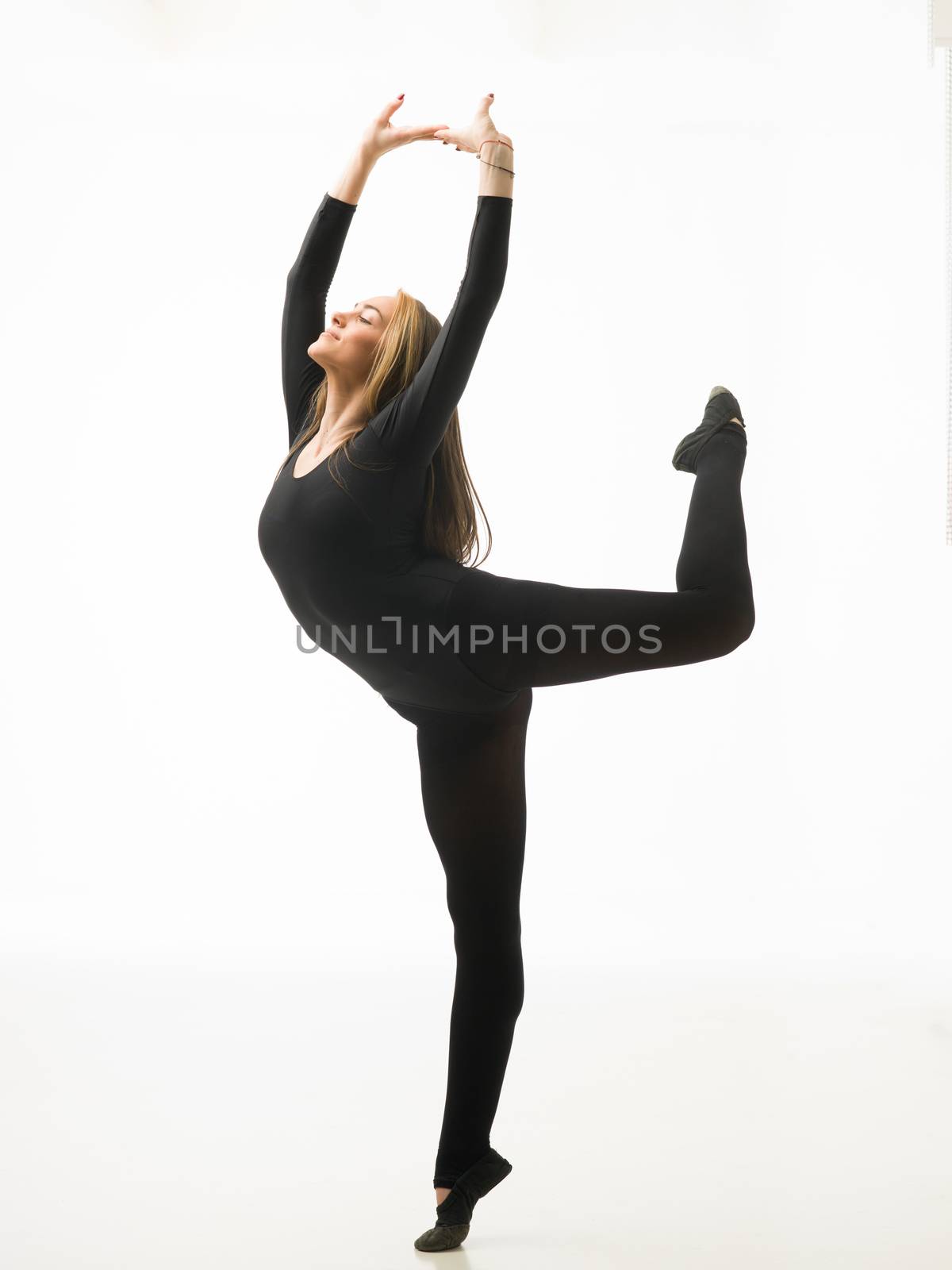 young beautiful dancer standing on tiptoe and posing, on white background
