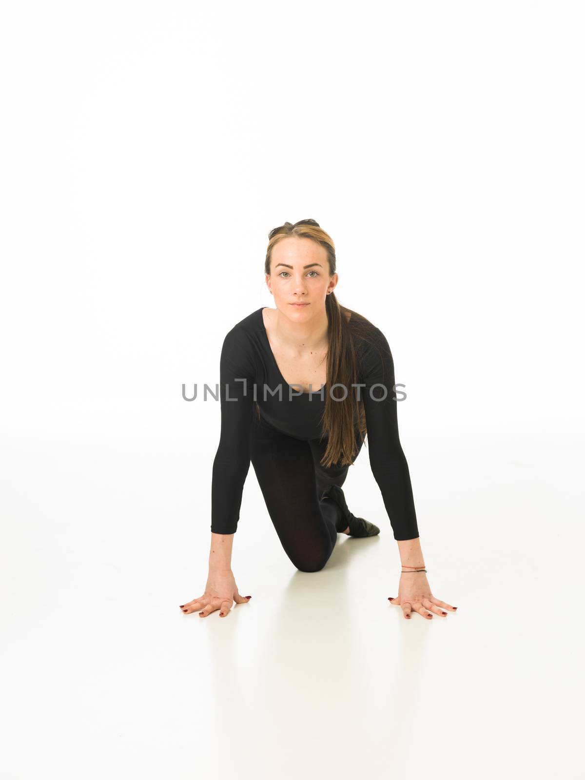beautiful ballet dancer sitting on studio floor looking in front of the camera, on white background