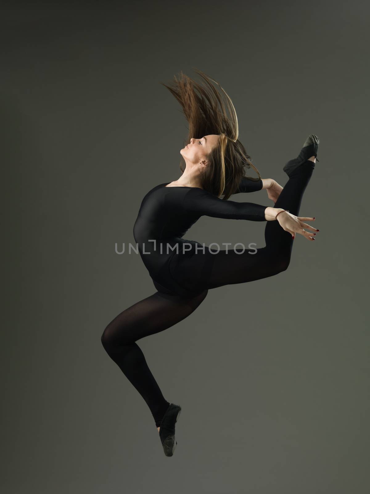 beautiful woman performing dance moves against grey background