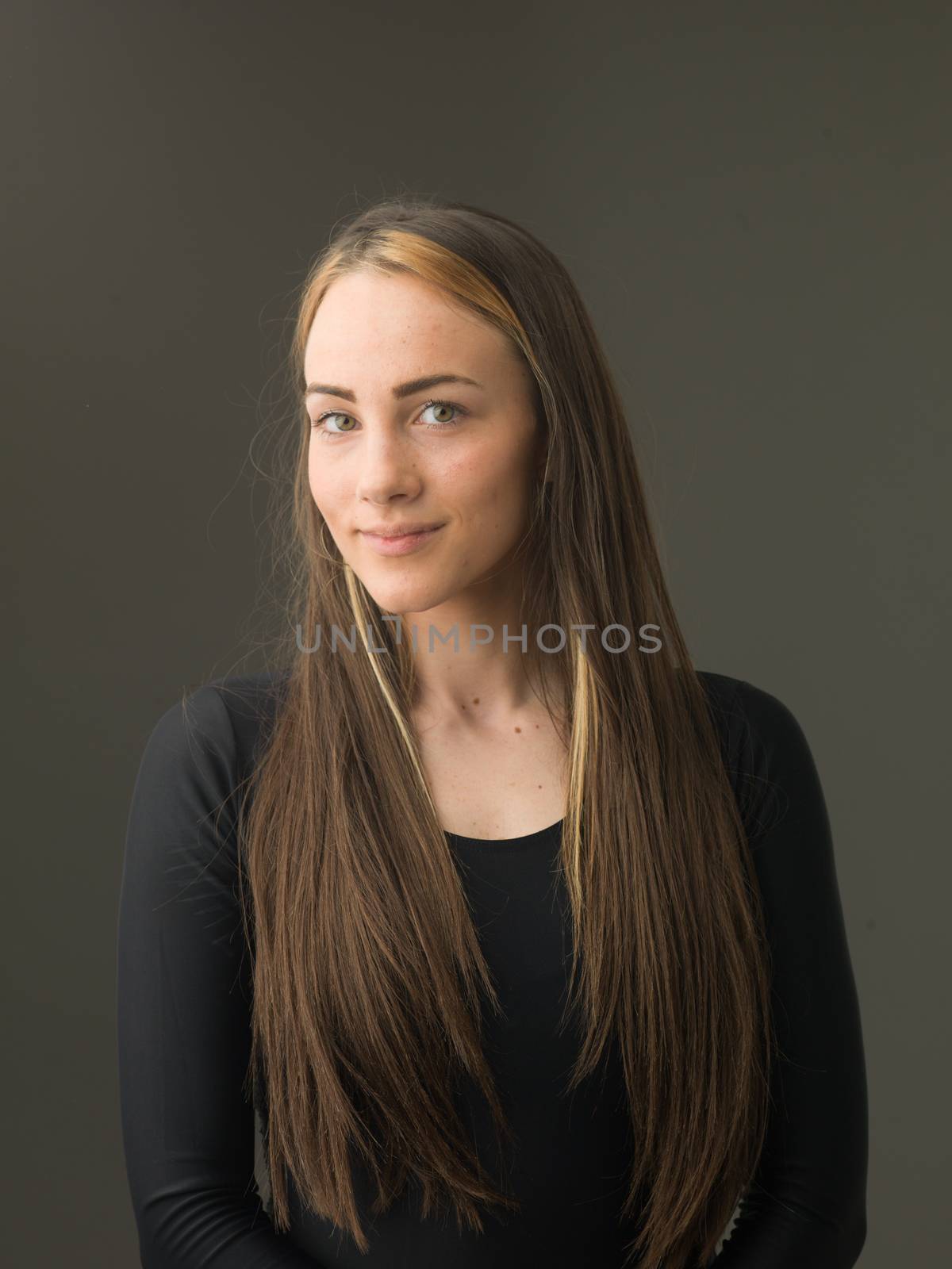 portrait of beautiful young woman with long blond hair, on grey background