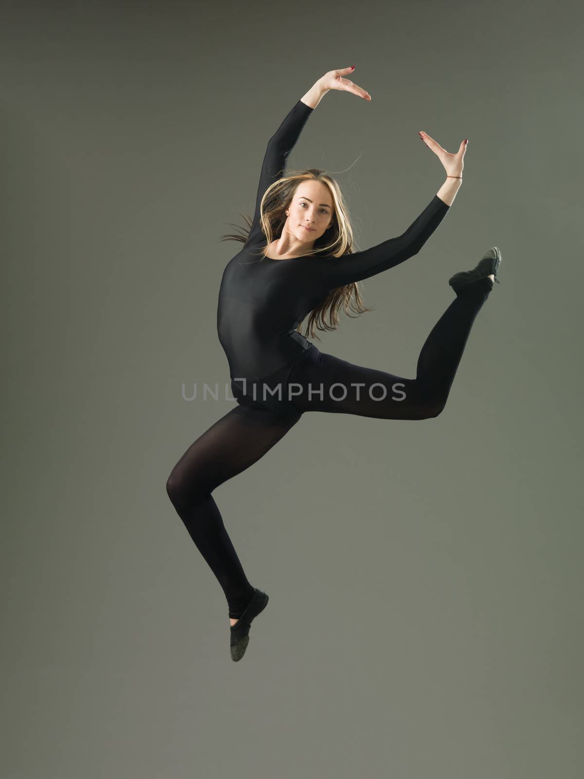 happy female dancer jumping against grey background