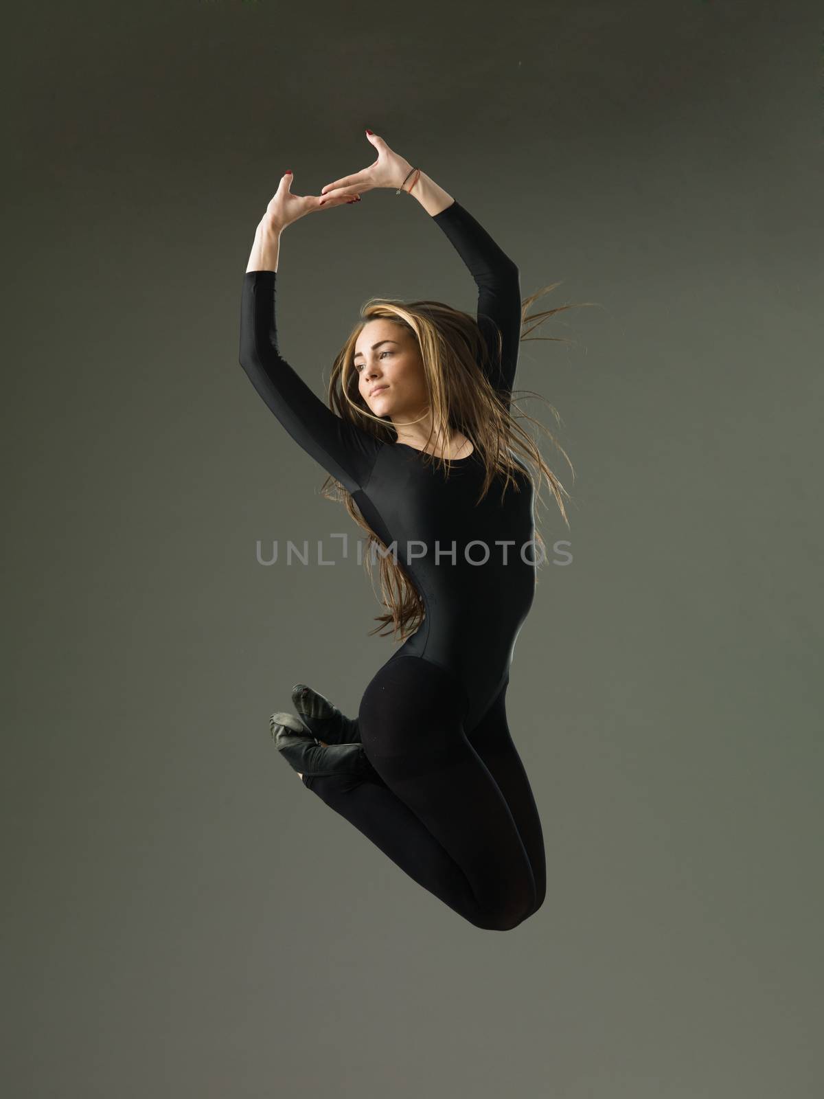 model dancer jumping and posing against grey studio background