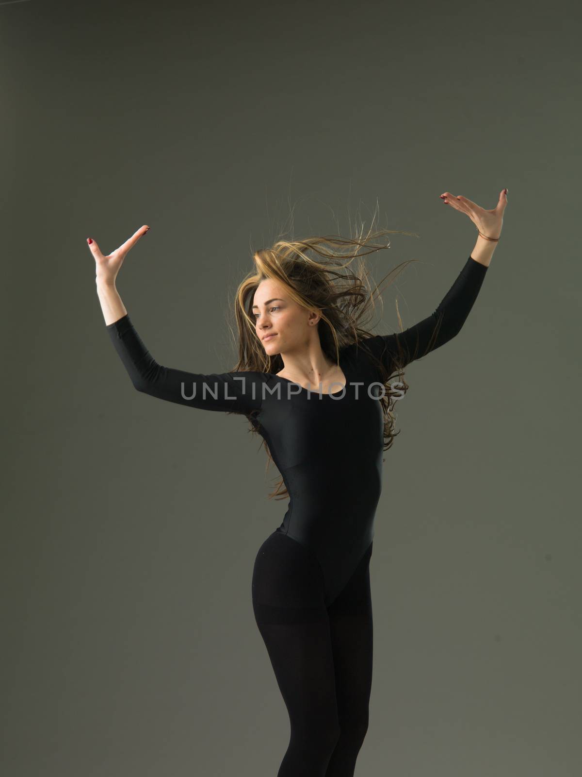 model dancer jumping and posing against grey studio background
