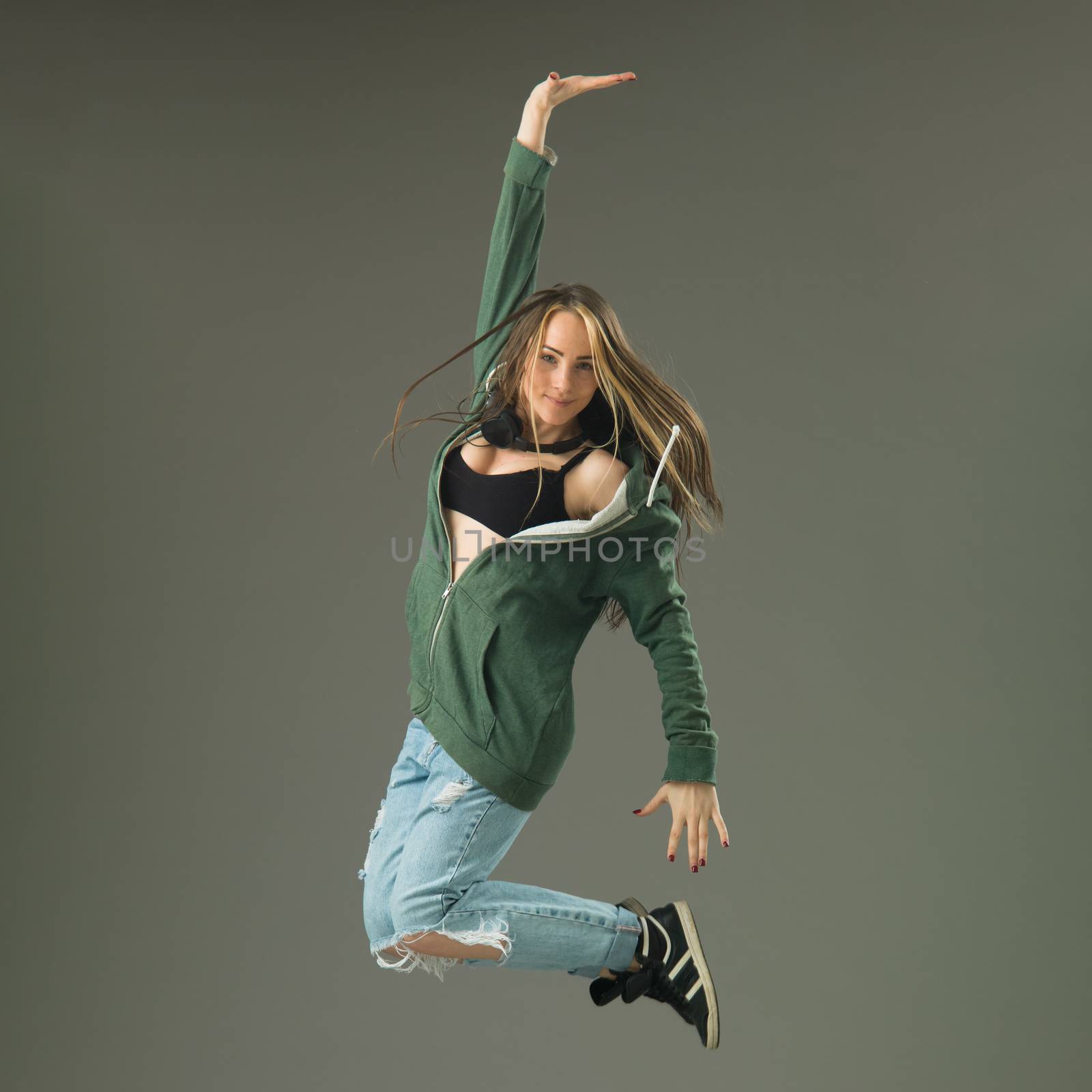 happy modern style dancer jumping against grey studio background