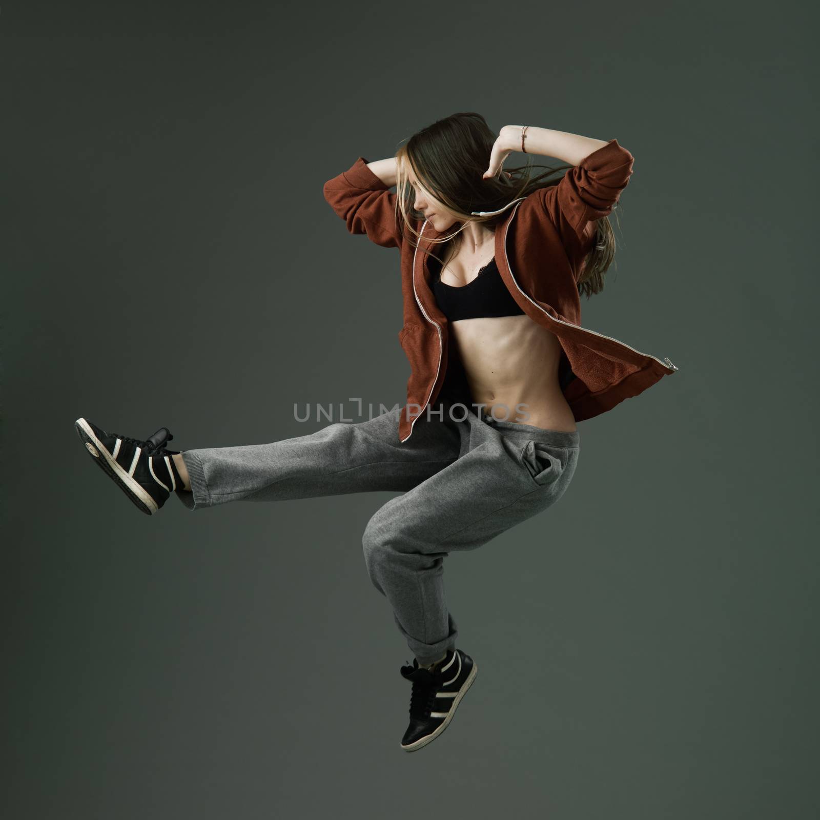 happy modern style dancer jumping against grey studio background