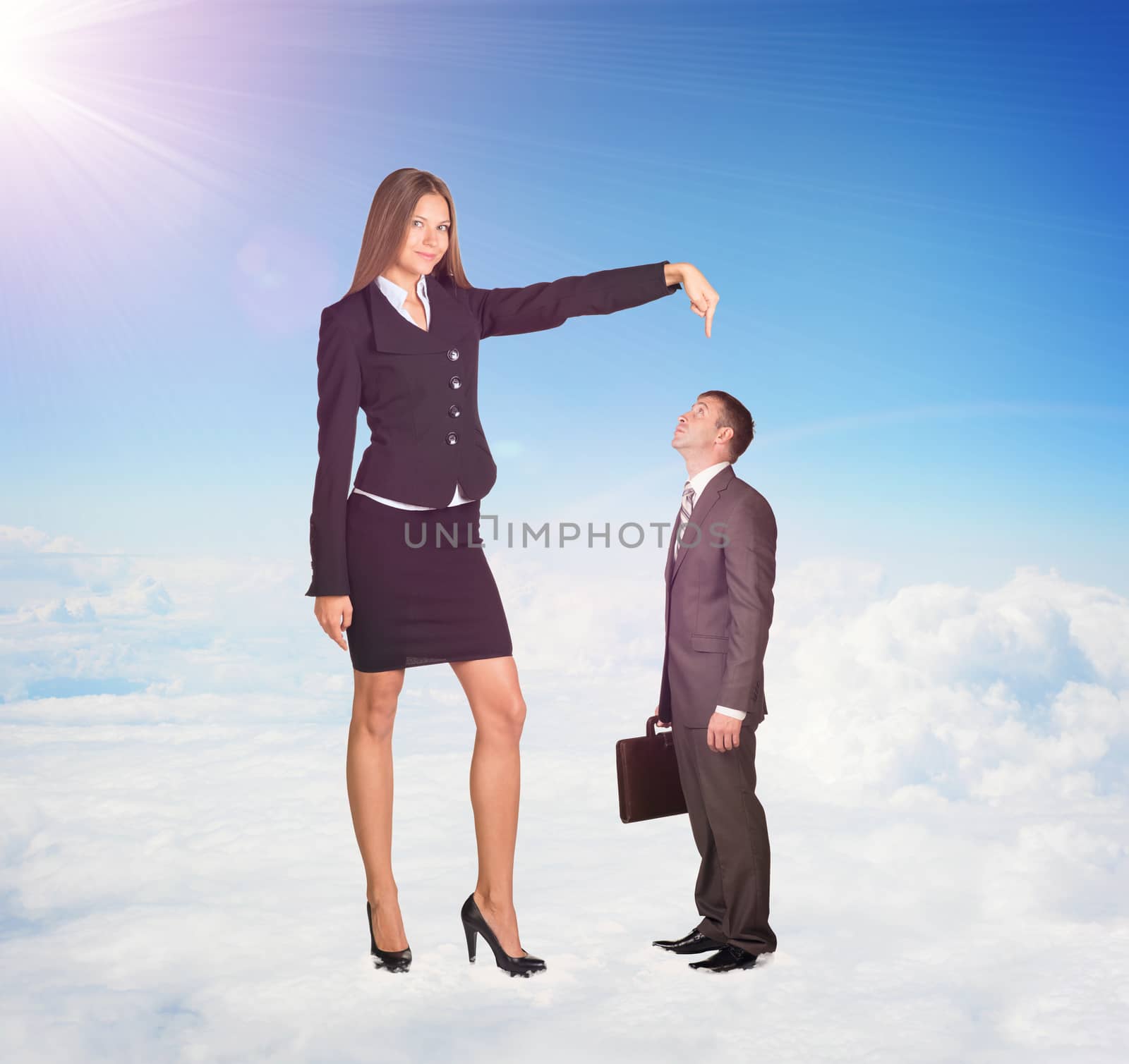 Small businessman looking up at large woman in suit. Clouds and cement surface as background. Business concept