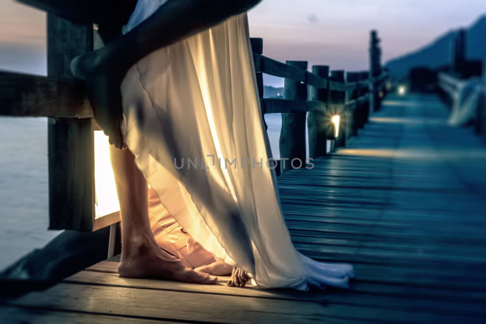 In the foreground, close photographed feet two people prinikshih to each other, lit a lantern at night in the beautiful wooden bridge leaving in perspective