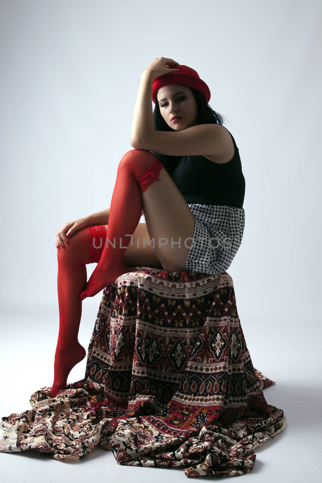 Young long-haired woman with red hat sitting thoughtfully on chair