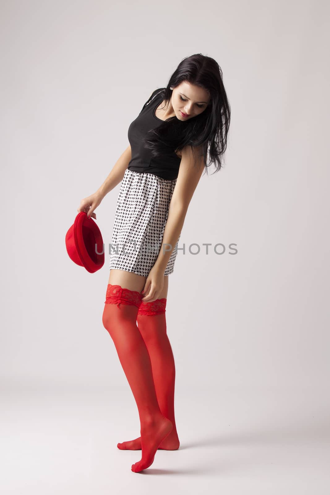 Young long-haired woman with red hat stand and corrects a red stocking