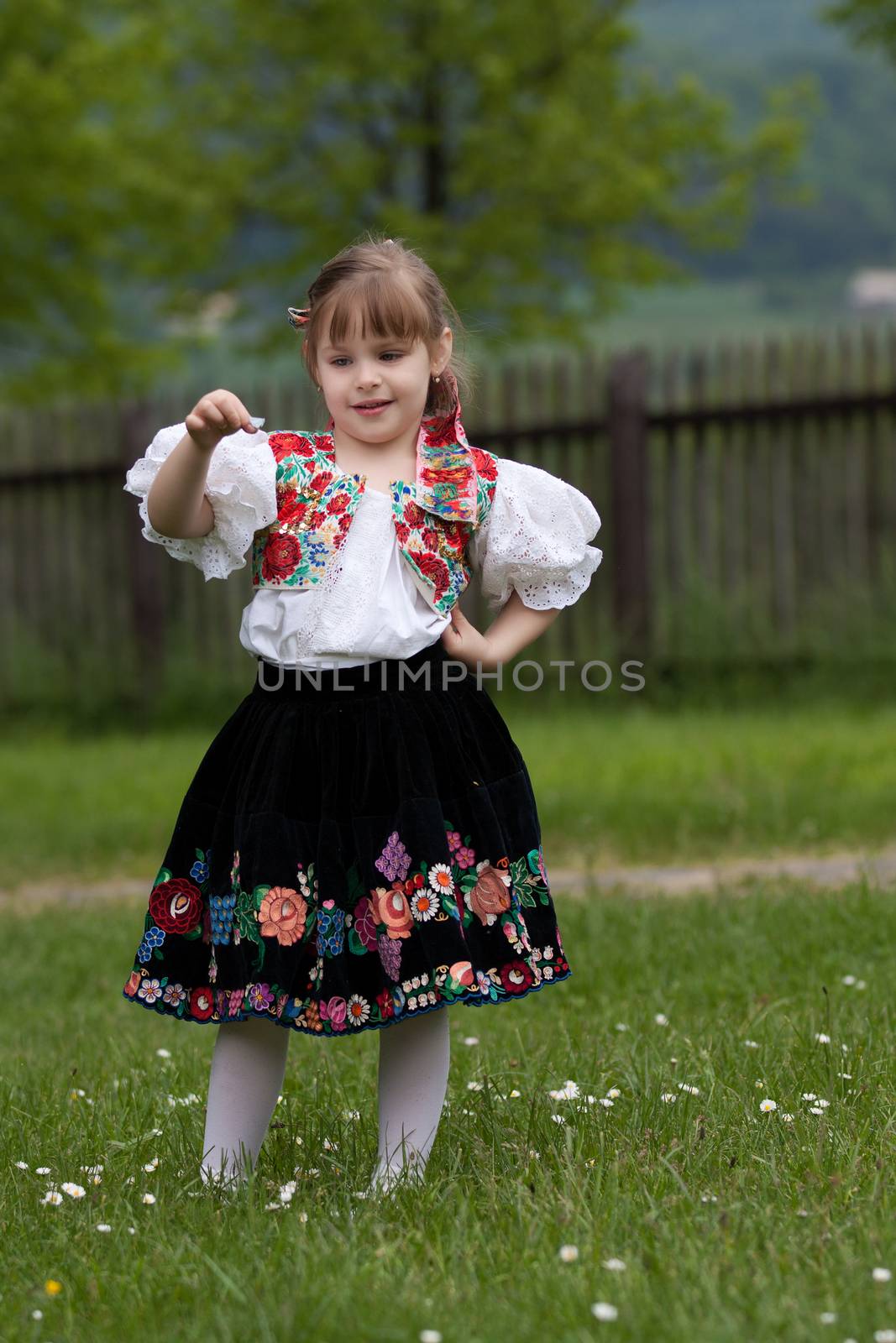 Little girl in costume on meadow, holding butterfly