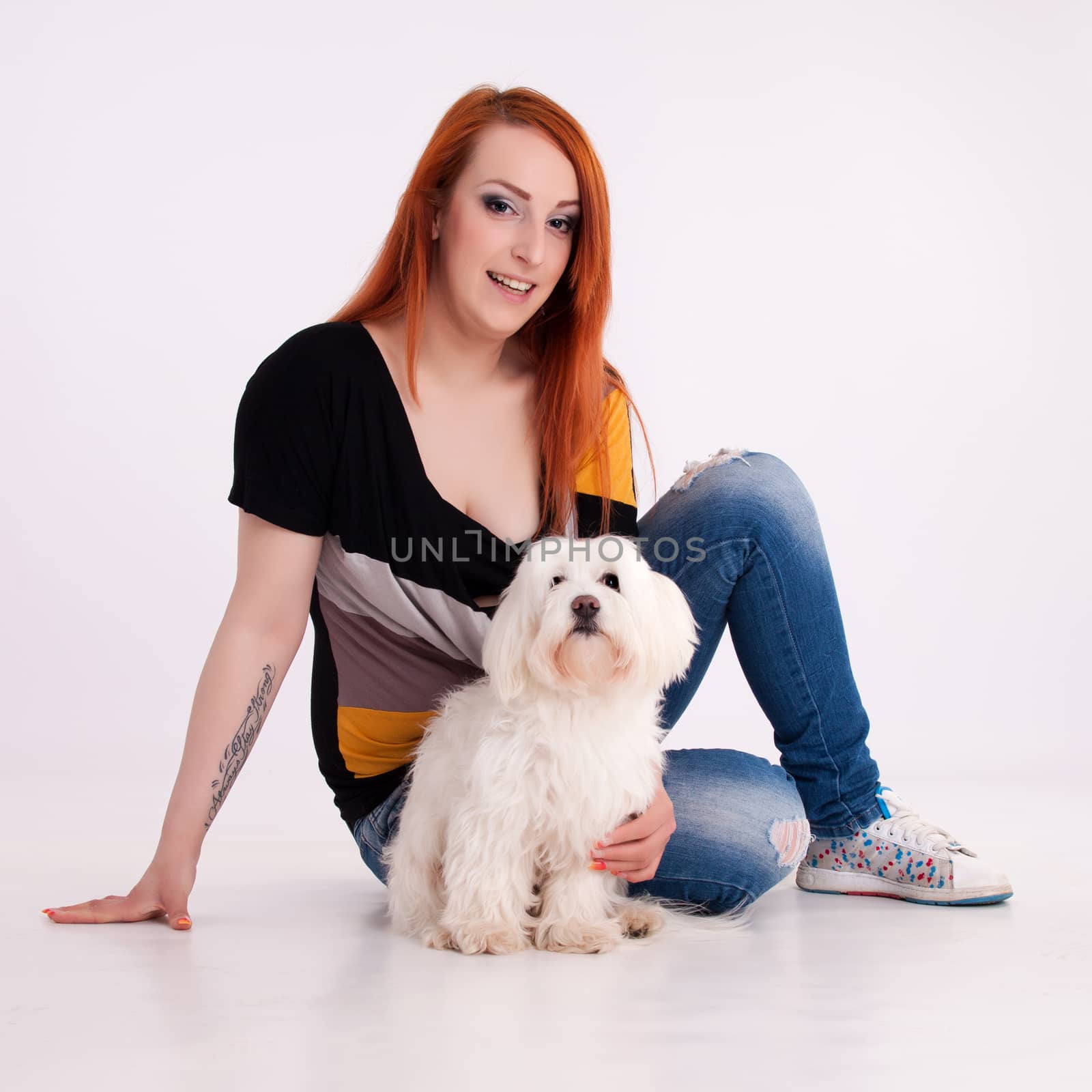 Young redhead woman with her white Maltese dog in studio