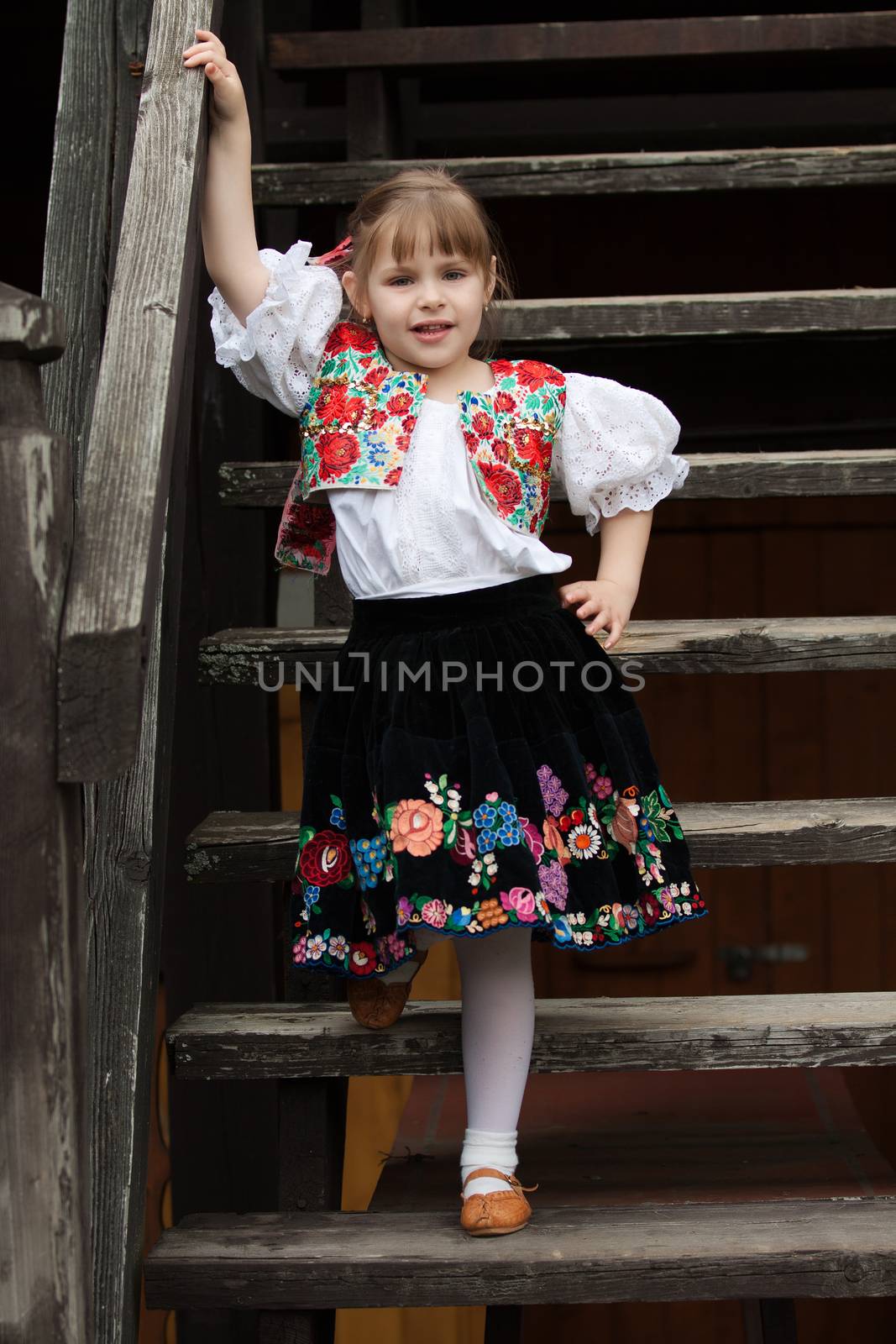 Little girl in traditional costume on the stairs by maros_b