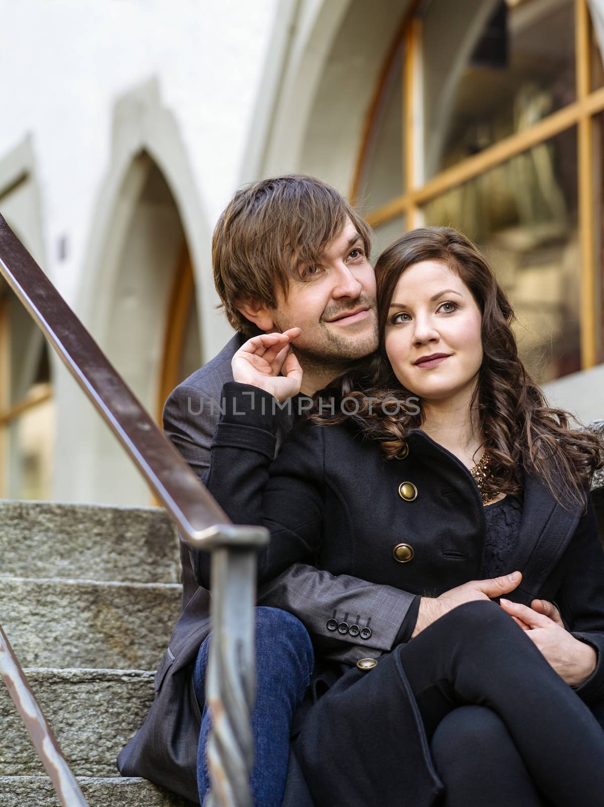 Photo of a young couple sitting and resting in an old town in Europe.
