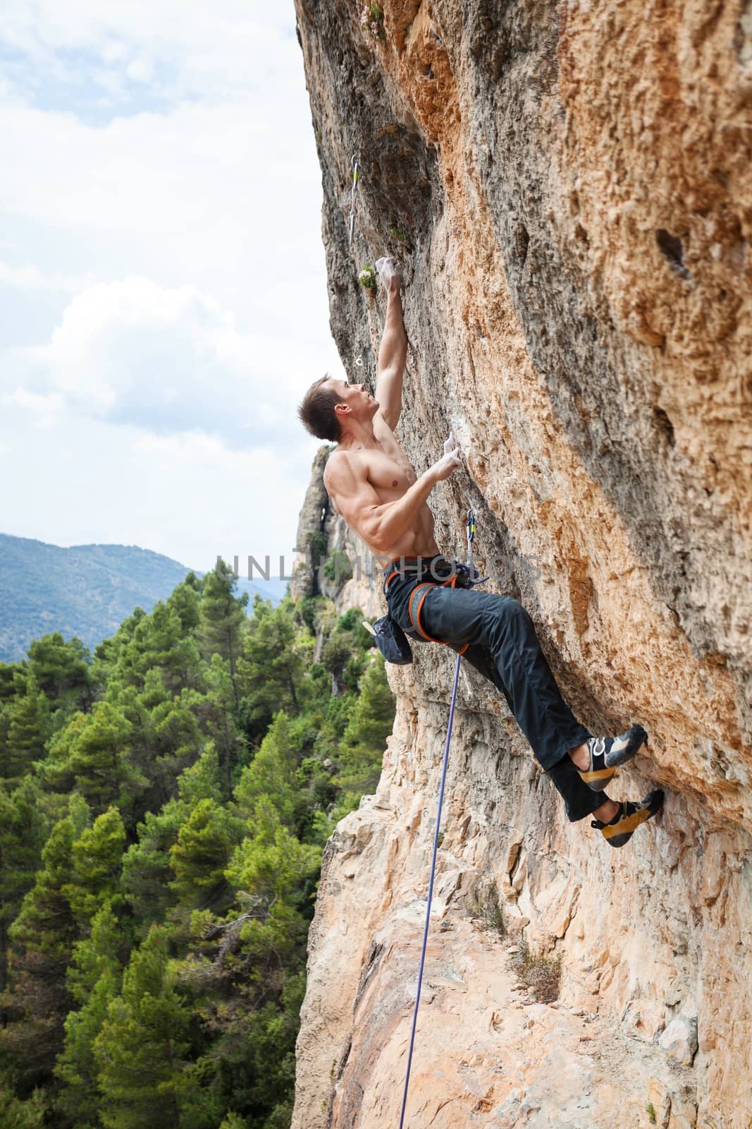 Male rock climber on challenging route on cliff by photobac