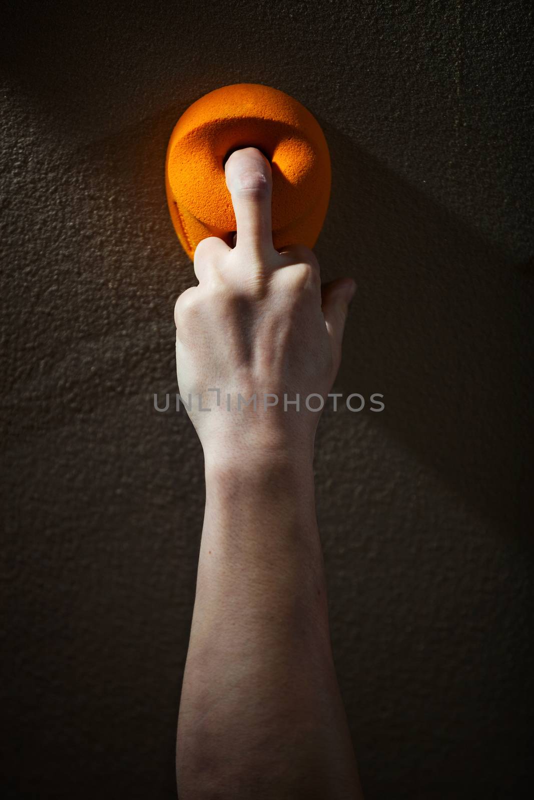 Rock climber gripping handhold with one finger by photobac