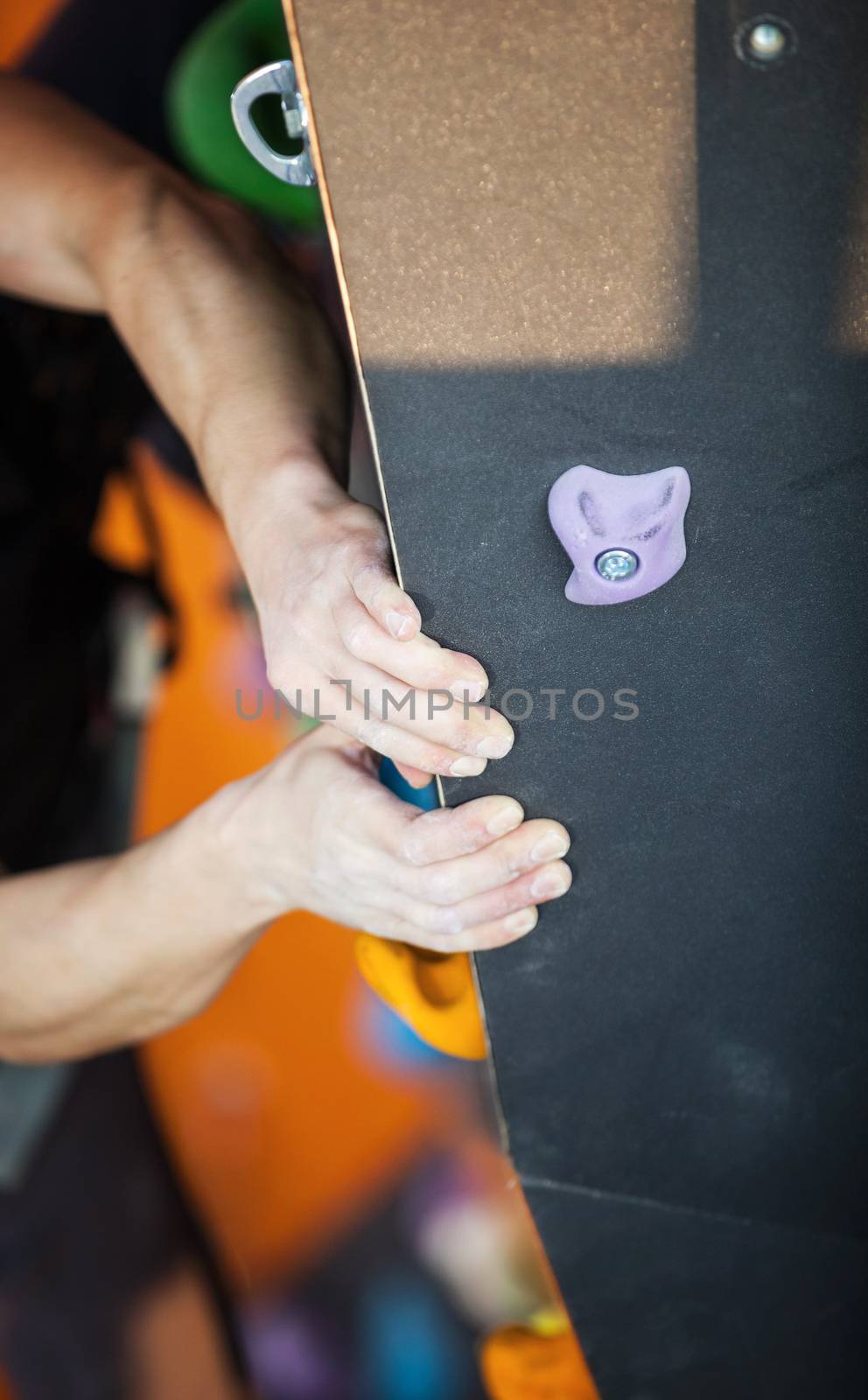 Rock climber's hands on artificial climbing wall indoors