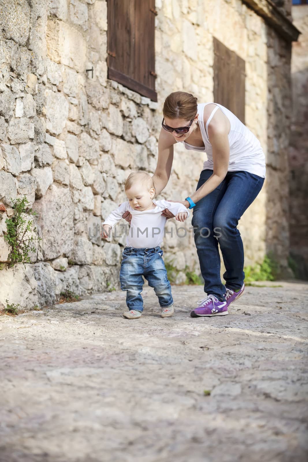 Cute baby boy makes his first steps with help of his mother