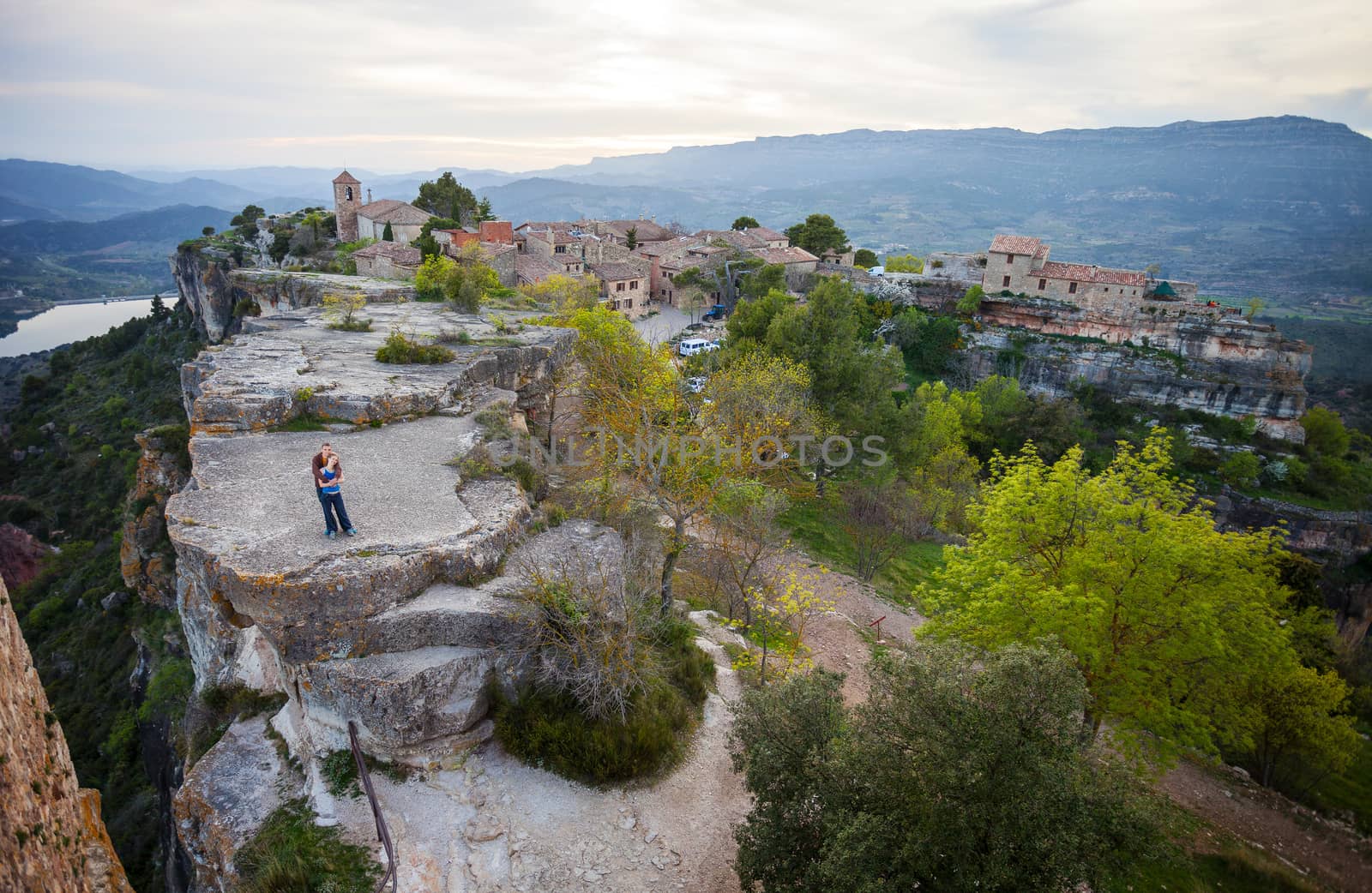 Young couple standing on cliff and enjoying valley view of old village Siurana