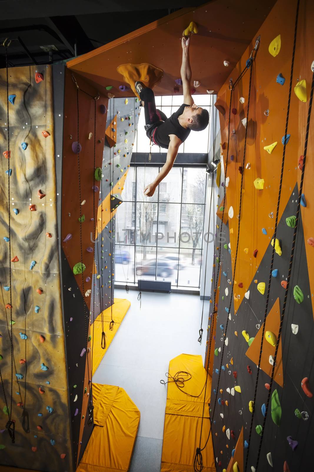 Man practicing top rope climbing in climbing gym by photobac