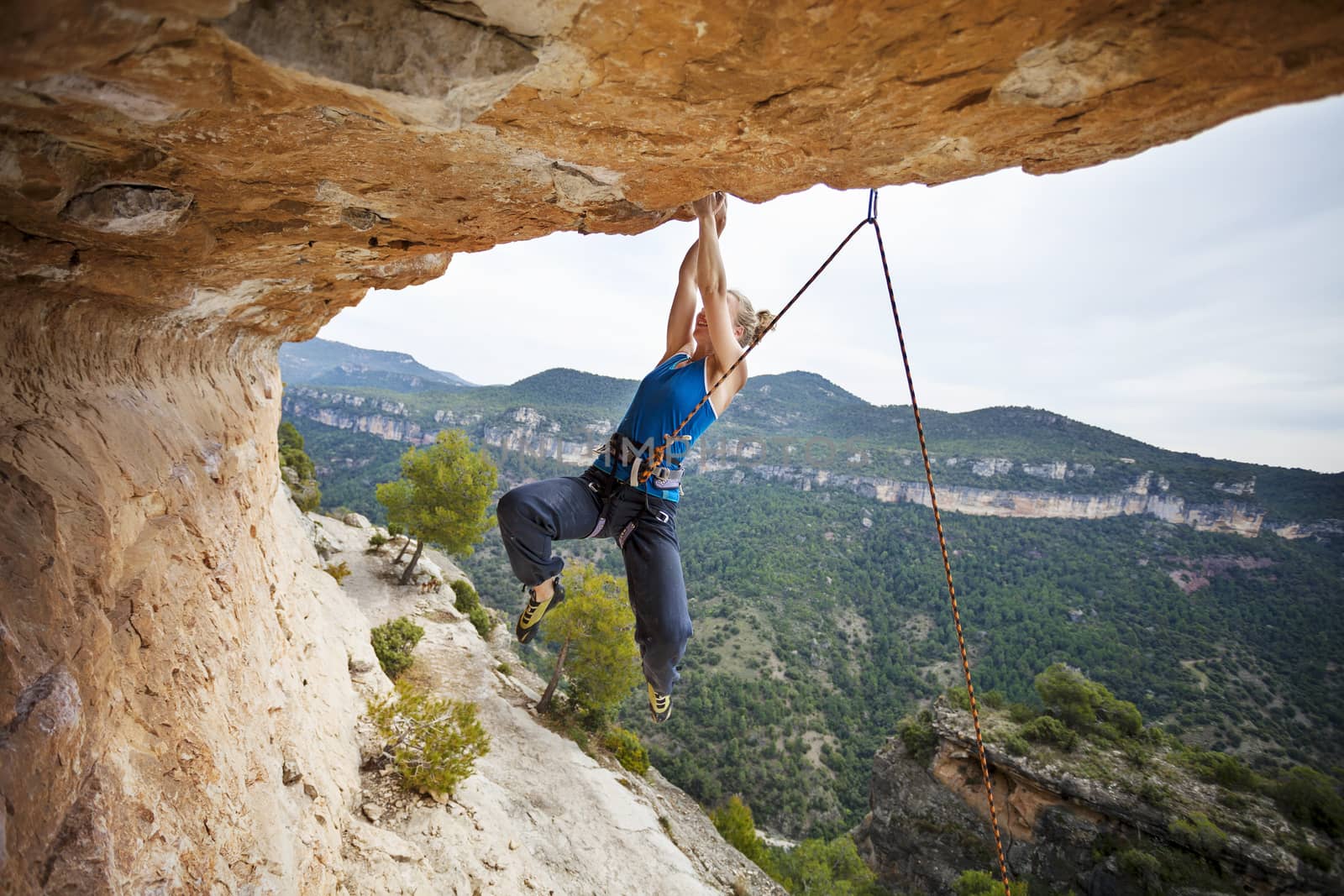 Woman climber struggling to make next movement up by photobac