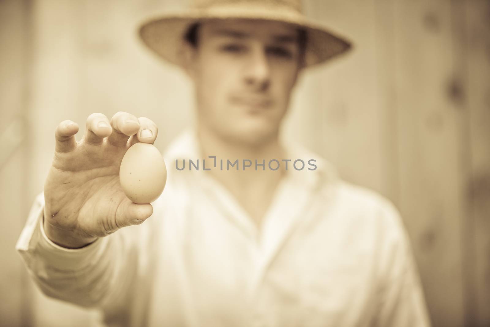 Farmer Showing an Egg in front of the Farm