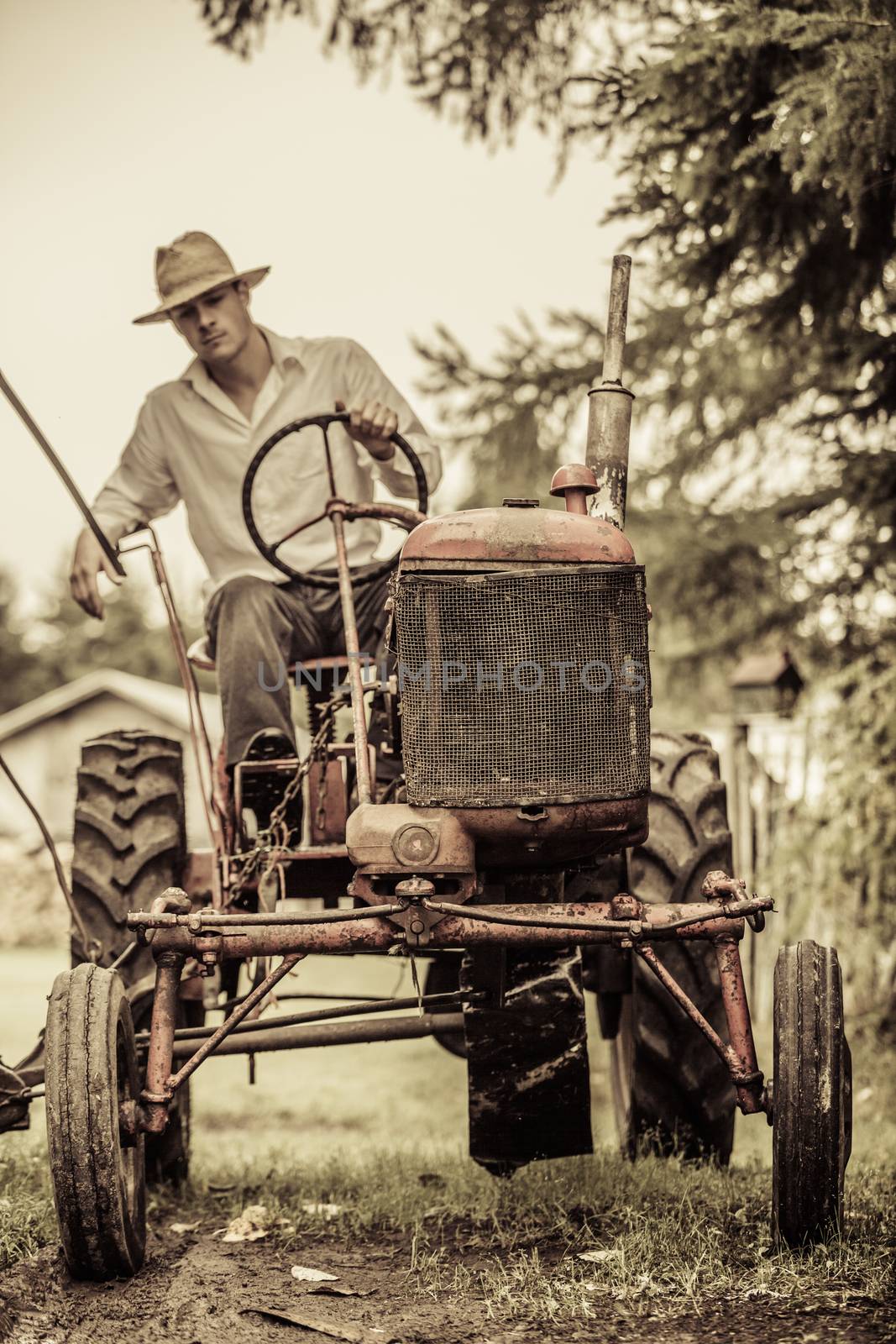 Young Farmer Driving a Red Old Vintage Tractor