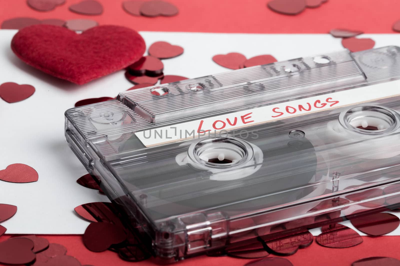 Audio cassette tape on red backgound with fabric heart, Valentine postcard. Love concept with evelope