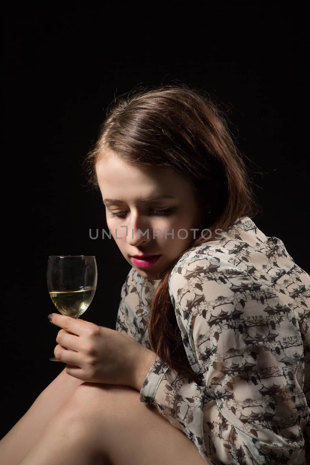 Smiling beautiful young brunette woman holding a glass of white wine and shoe