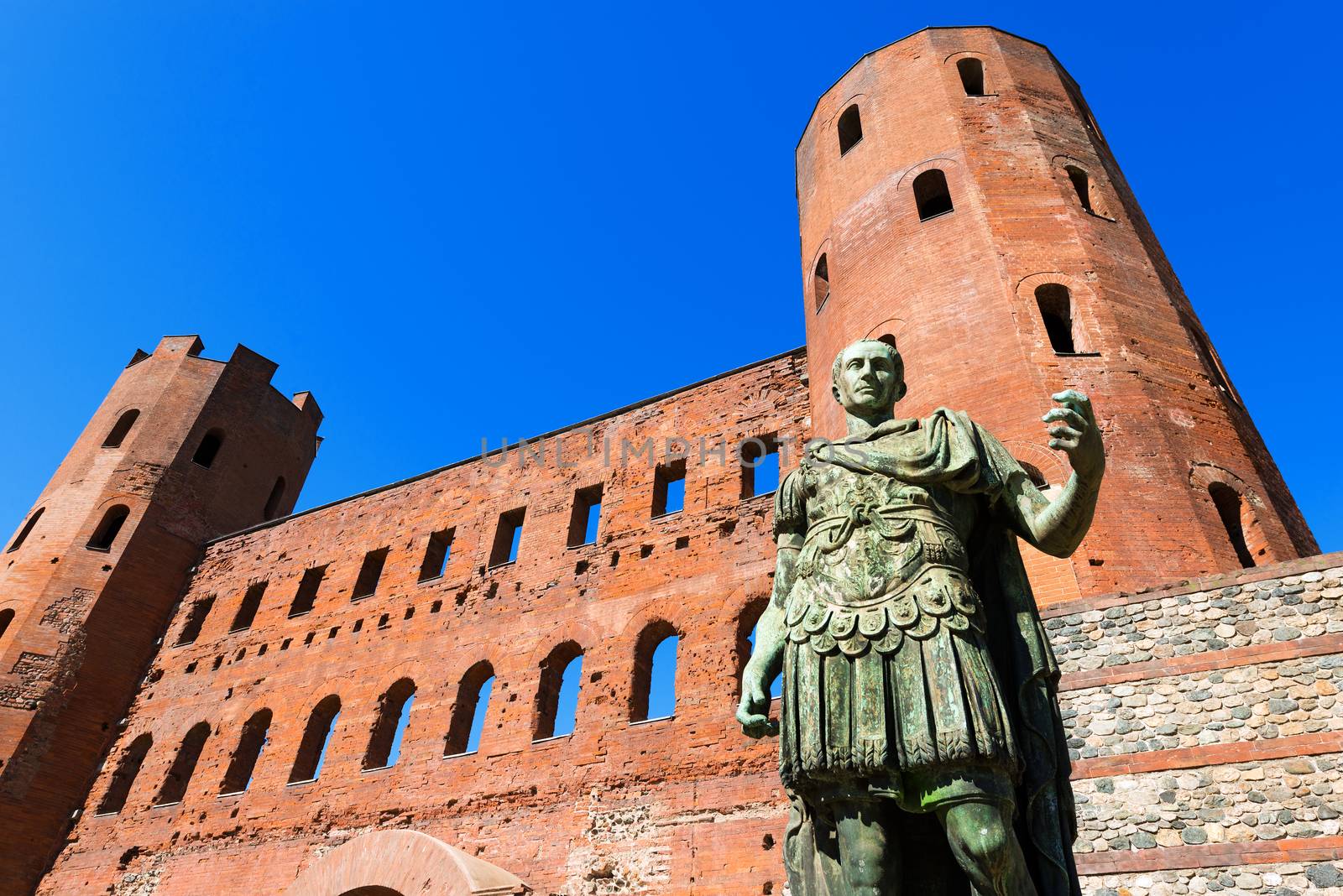 Roman statue of Julius Caesar and ancient ruins of Palatine Towers in Torino, Piemonte, Italy
