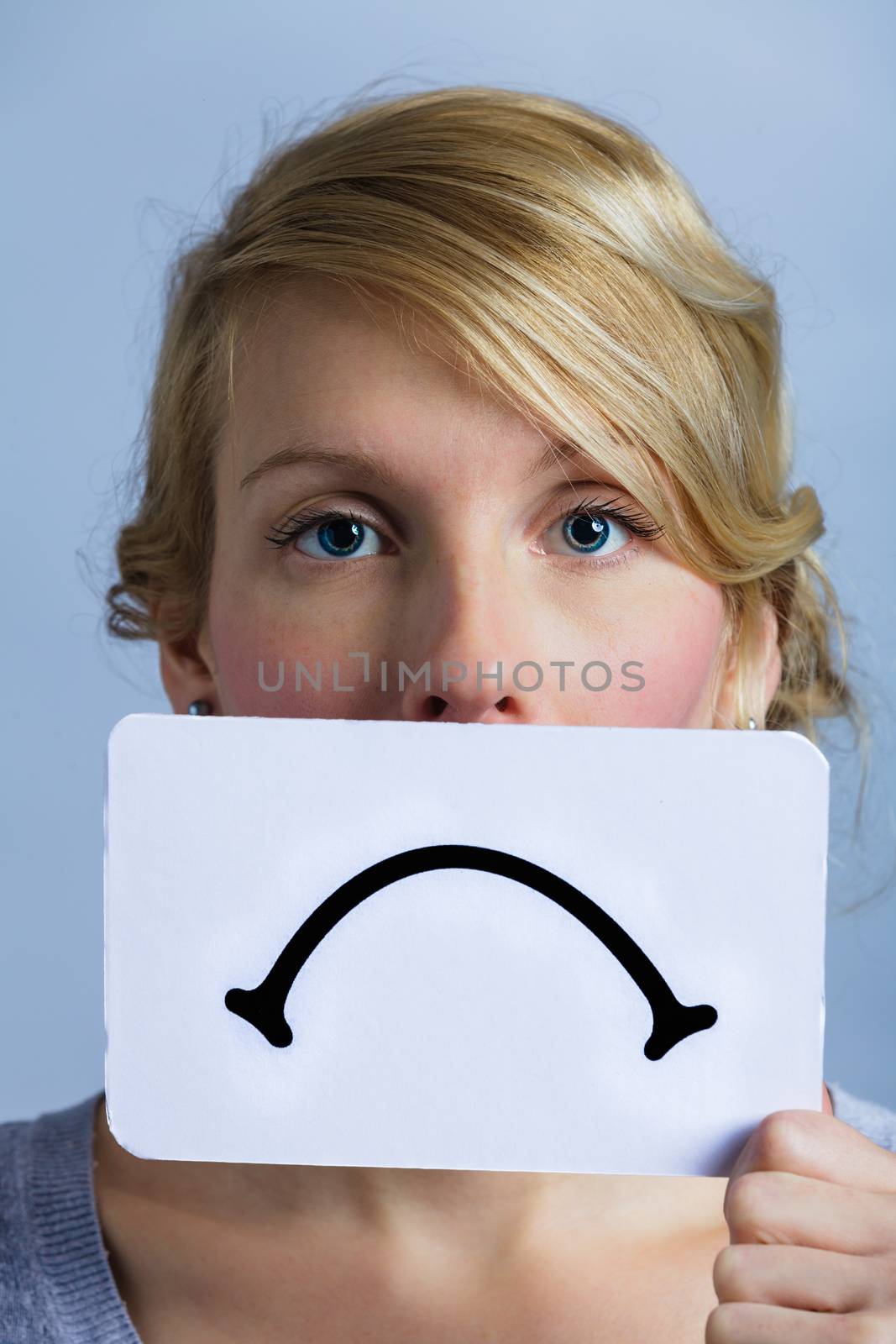 Unhappy Portrait of a Woman Holding a Sad Mood Board with Blue Background