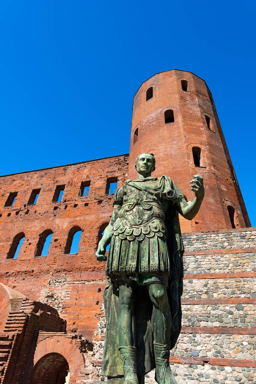 Roman statue of Julius Caesar and ancient ruins of Palatine Towers in Torino, Piemonte, Italy