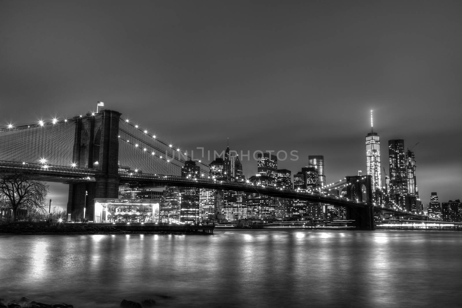 Brooklyn bridge and New York City Manhattan downtown skyline at dusk with skyscrapers illuminated over East River panorama. Copy space. Black and white image.