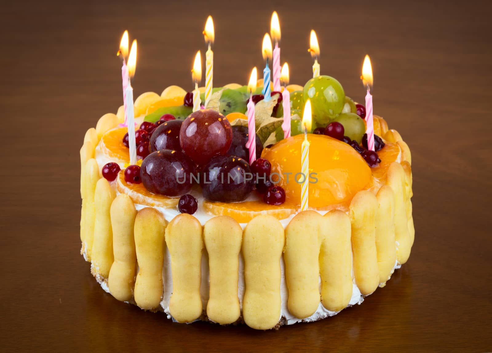 Happy birthday fruit cake with candles on wooden table background