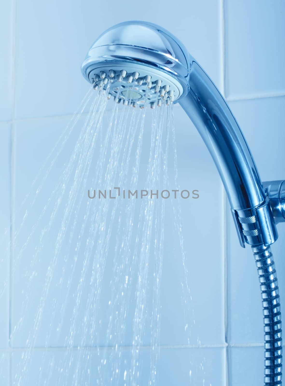 Silver shower head with flowing water in the bathroom