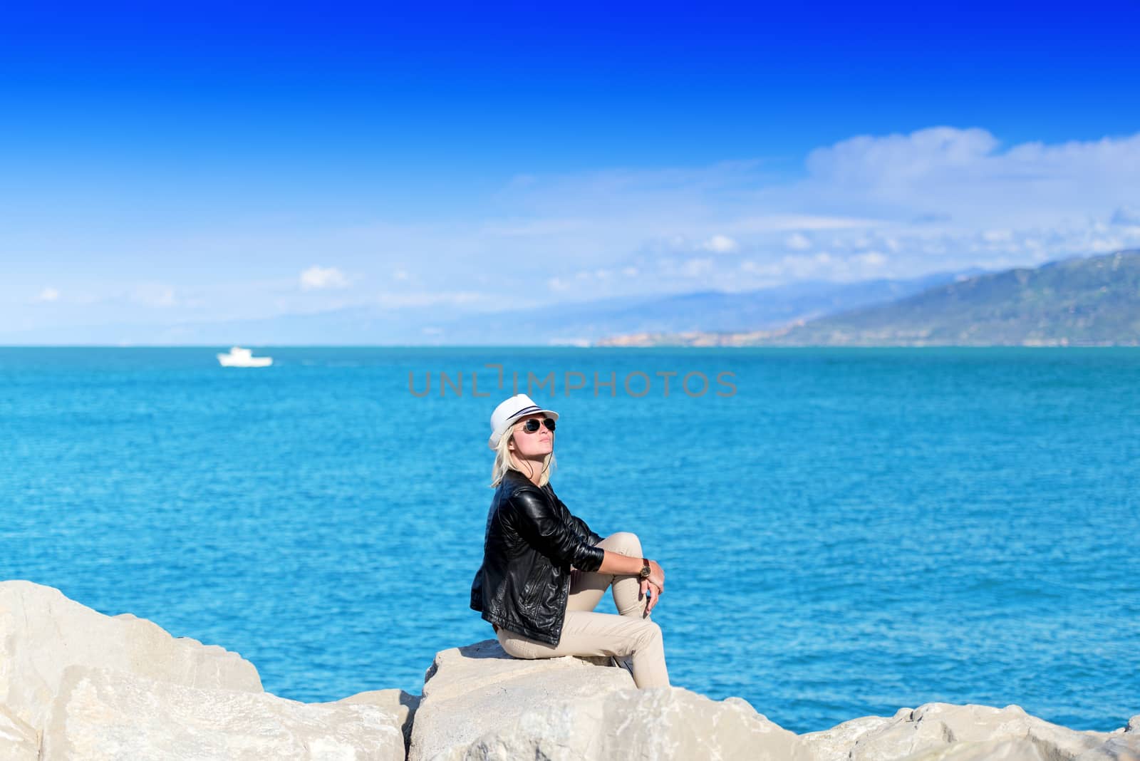 Attractive young woman sunbathing on rocks by Nanisimova