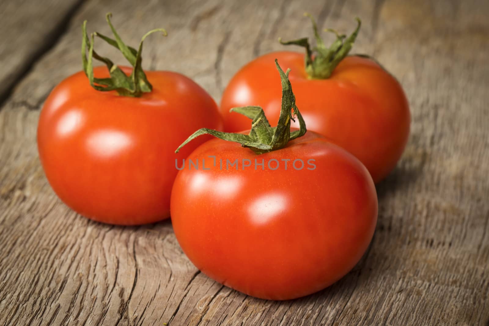 Three ripe tomatoes on wooden background